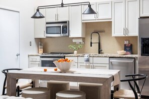 Uma cozinha moderna com armários brancos, micro-ondas, pia e área de refeições com mesa e cadeiras.