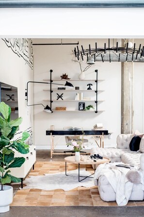 Un salon moderne avec un canapé blanc, une table basse et un bureau doté d’étagères.