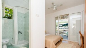 Een badkamer met douche, toilet en een bed met uitzicht op het buiten.