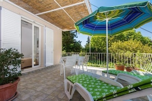 A patio with a covered seating area, a table, and a potted plant.