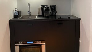 A compact kitchen with a built-in oven, a coffee maker, and a bottle of hand sanitizer. - Appartement indépendant Tour Eiffel/ Invalides (Paris)