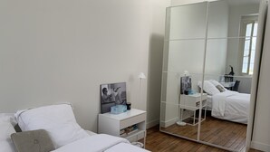 A bedroom with a bed, bedside table, lamp, and a large mirror. - Appartement indépendant Tour Eiffel/ Invalides (Paris)
