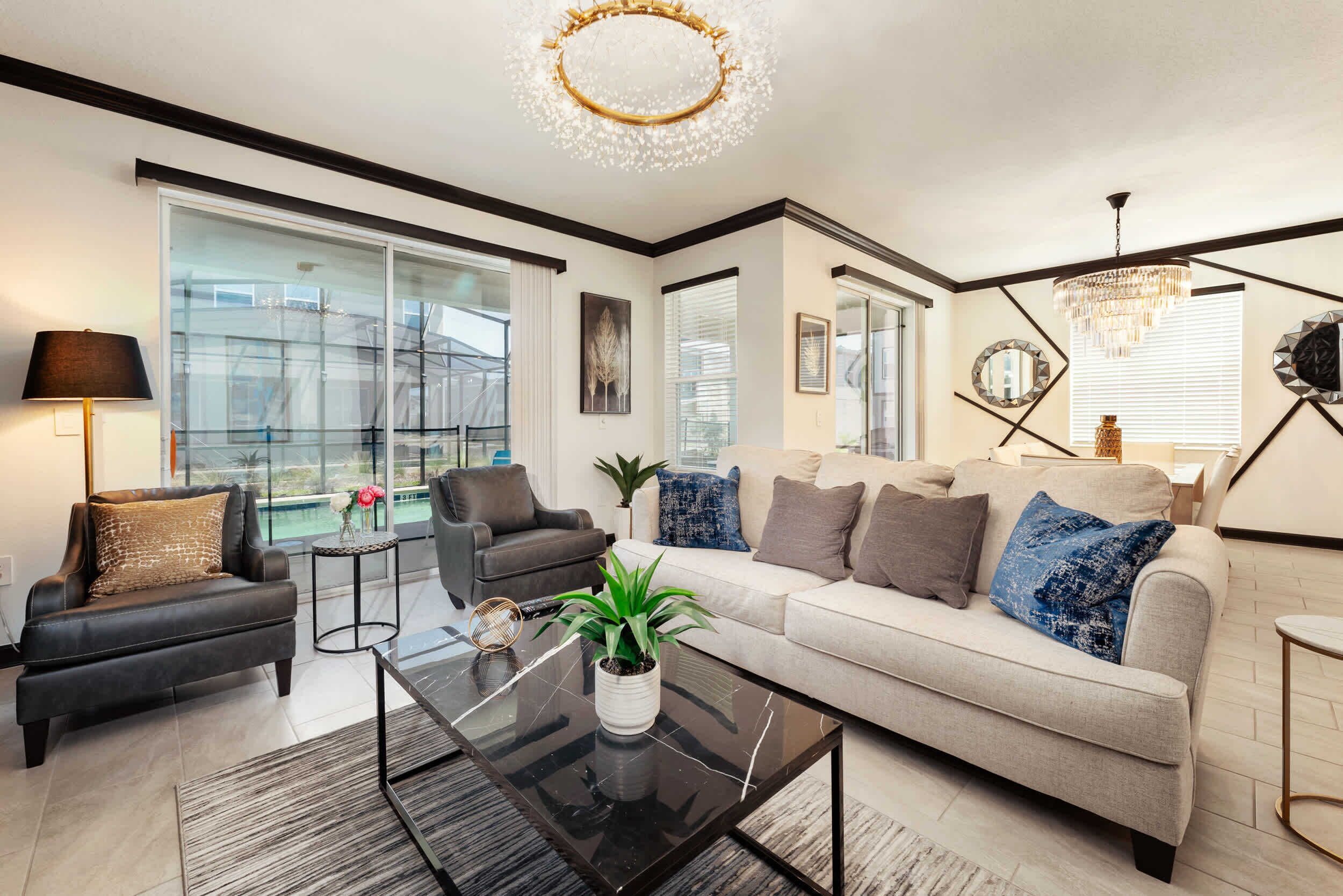 A modern living room with a sofa, armchairs, a coffee table, and a chandelier.