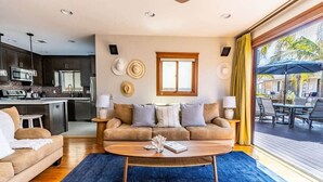A modern living room with a sofa, coffee table, and dining area. - Mission Beach Retreat, Steps to Bay & Beach (San Diego)
