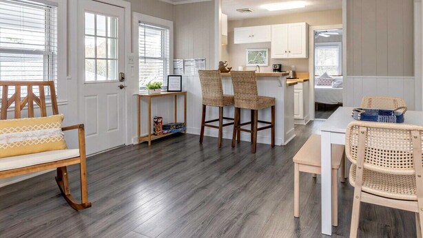 A modern kitchen with white cabinets, a dining area with wicker chairs, and a wooden bench. - Beachwalk #4, 8 minute walk to the beach (Virginia Beach)