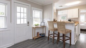 A kitchen with white cabinets, a wooden countertop, and a wicker chair. - Beachwalk #4, 8 minute walk to the beach (Virginia Beach)