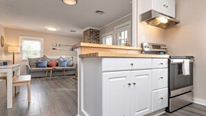 A modern kitchen with white cabinetry, a built-in oven, and a countertop with a range hood. - Beachwalk #4, 8 minute walk to the beach (Virginia Beach)