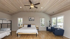 A bedroom with a bunk bed, a single bed, a ceiling fan, and large windows. - The VIBE House with POOL! (Virginia Beach)