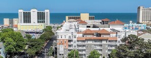 Un paisaje urbano costero con varios edificios, incluyendo un hotel destacado de diseño moderno y vistas al mar.