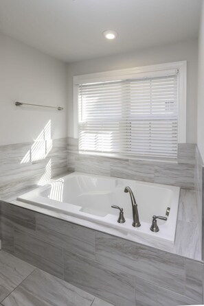 Un baño moderno con una bañera independiente, una ventana con persianas y un perchero para toallas.