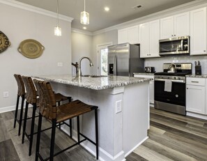 Enjoy cooking in this well-equipped kitchen with a central island, stainless steel sink, and double oven.