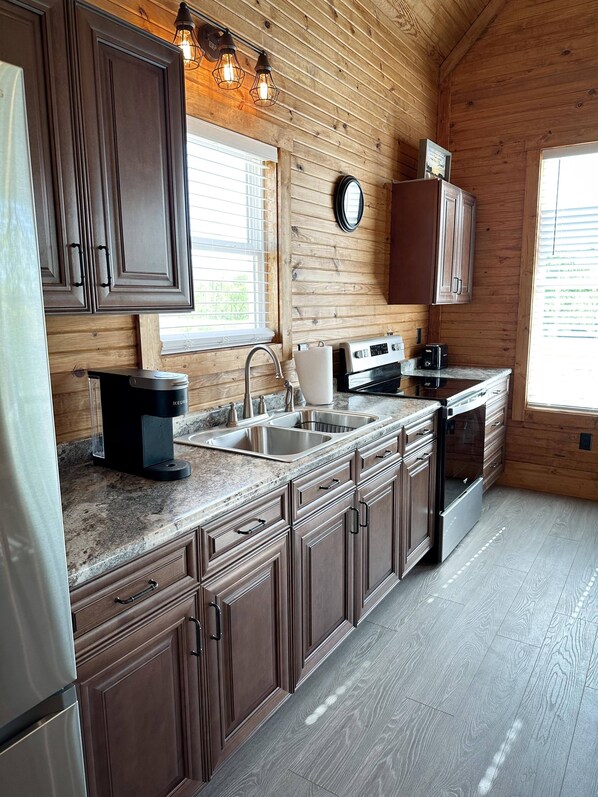 A kitchen with wooden cabinets, a granite countertop, a coffee maker, a toaster, and a stove.