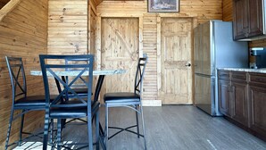 A rustic wooden interior with a dining area, a kitchen, and a staircase.