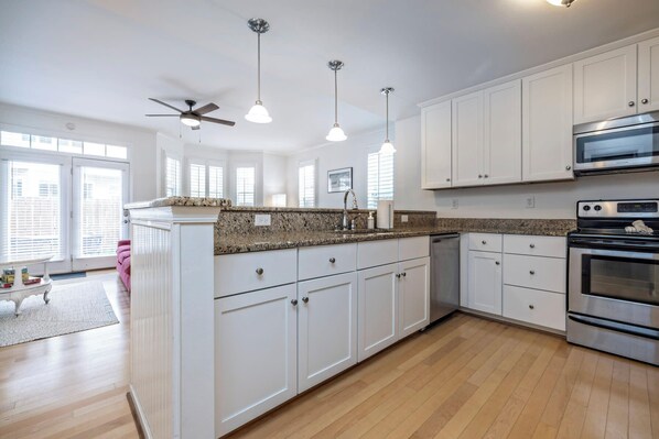 A modern kitchen with white cabinets, granite countertops, a built-in oven, and a ceiling fan. - Incredible Location! Amazing Comfort! (Virginia Beach)