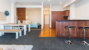 Ein modernes Apartment mit Essbereich, Küche und einem Flur, der zum Schlafzimmer führt.