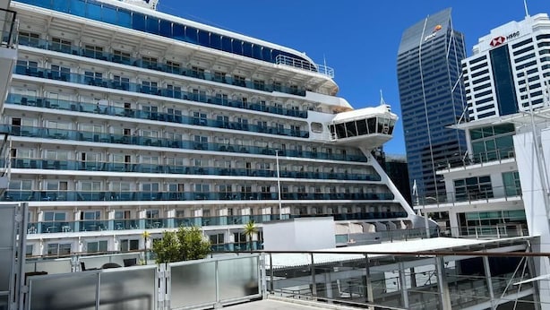 Ein modernes Kreuzfahrtschiff mit mehreren Decks, großen Fenstern und einer weißen Außenhülle.
