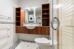 A bathroom with a white sink, wooden vanity, and a glass shower enclosure. - Waterfront Seaview Apt Hotel (Auckland)