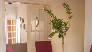 A dining area with a glass table surrounded by four red chairs, a vase with flowers, and a door leading to another room. - Kerr Ayo's One Bedroom Apartment, 5 minutes Away from Senegambia Beaches. (Serrekunda)