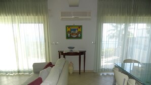 Una sala de estar con sofá, una mesa de comedor con sillas y un equipo de aire acondicionado en la pared.