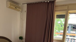 A bedroom with a bed, pillows, a nightstand, a potted plant, and a view of the outside. - İstanbul Apartment (Belgrade)