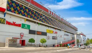 A shopping center with a colorful facade, including signs for McDonald's, New Yorker, and Takko. - İstanbul Apartment (Belgrade)