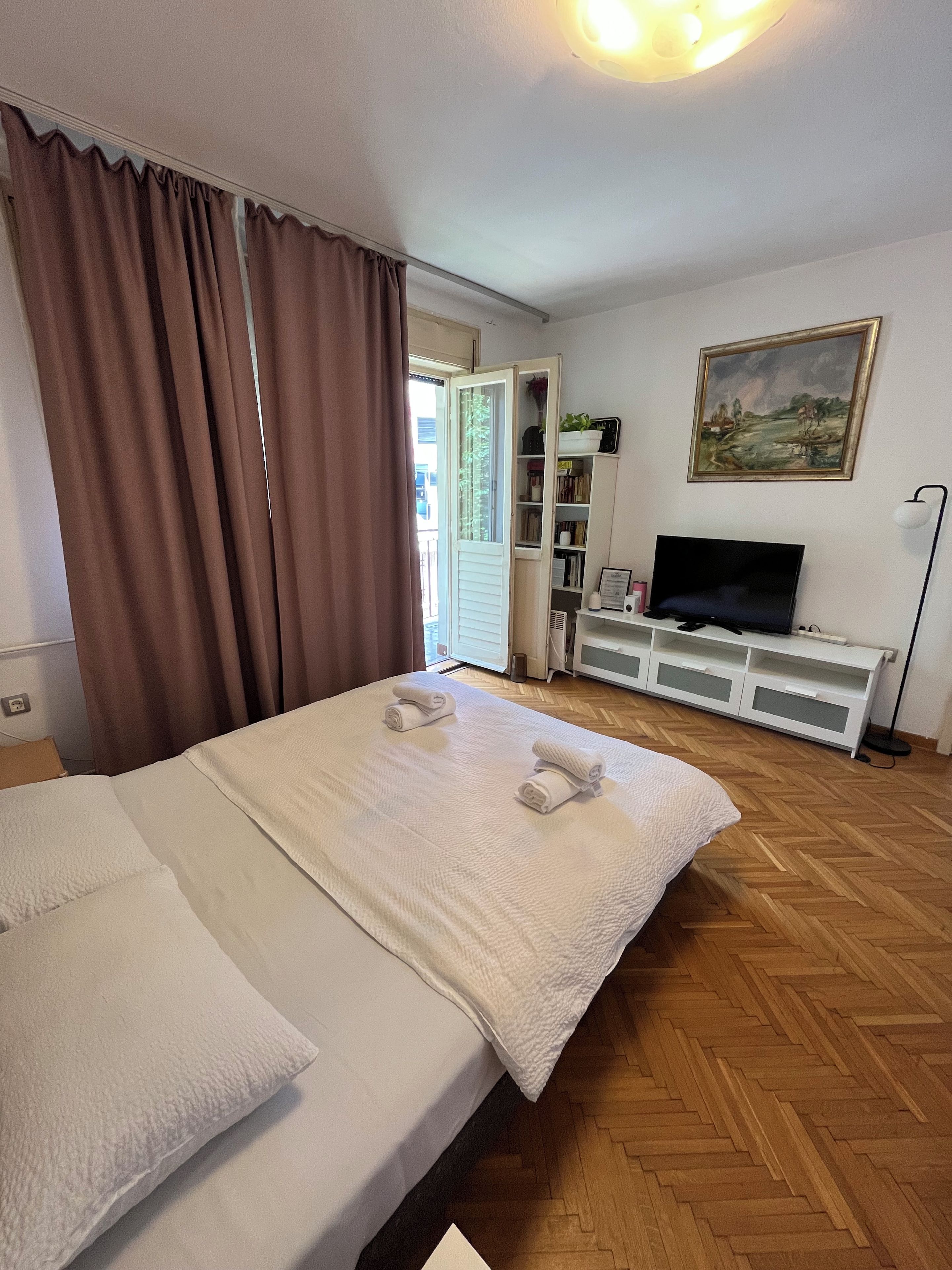 Une chambre d’hôtel avec un lit, une télévision, une bibliothèque et un tableau au mur.