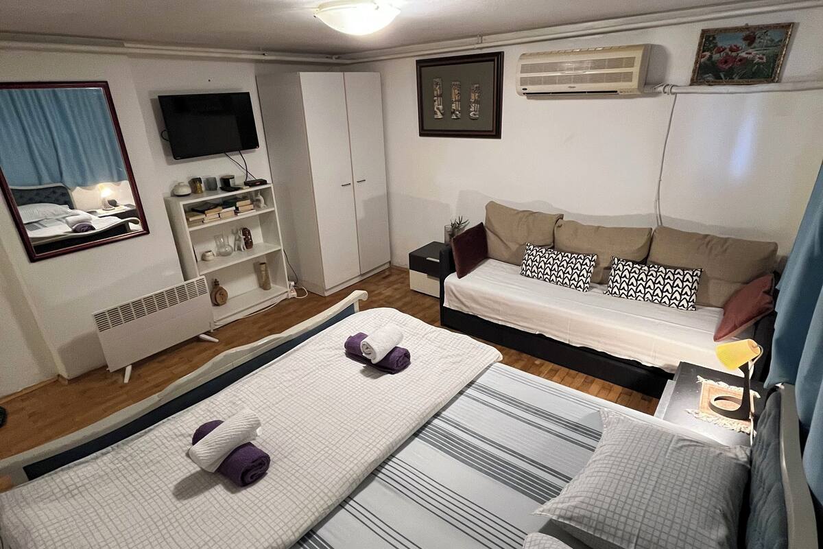 Une chambre d’hôtel avec deux lits, un canapé, une télévision et une petite table.