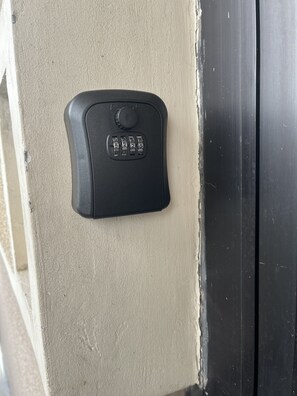 A black security keypad attached to a beige wall, likely for a door or gate. - İstanbul Apartment (Belgrade)