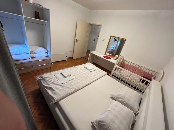 Un dormitorio con una cama individual doble, un escritorio con espejo y una cuna.