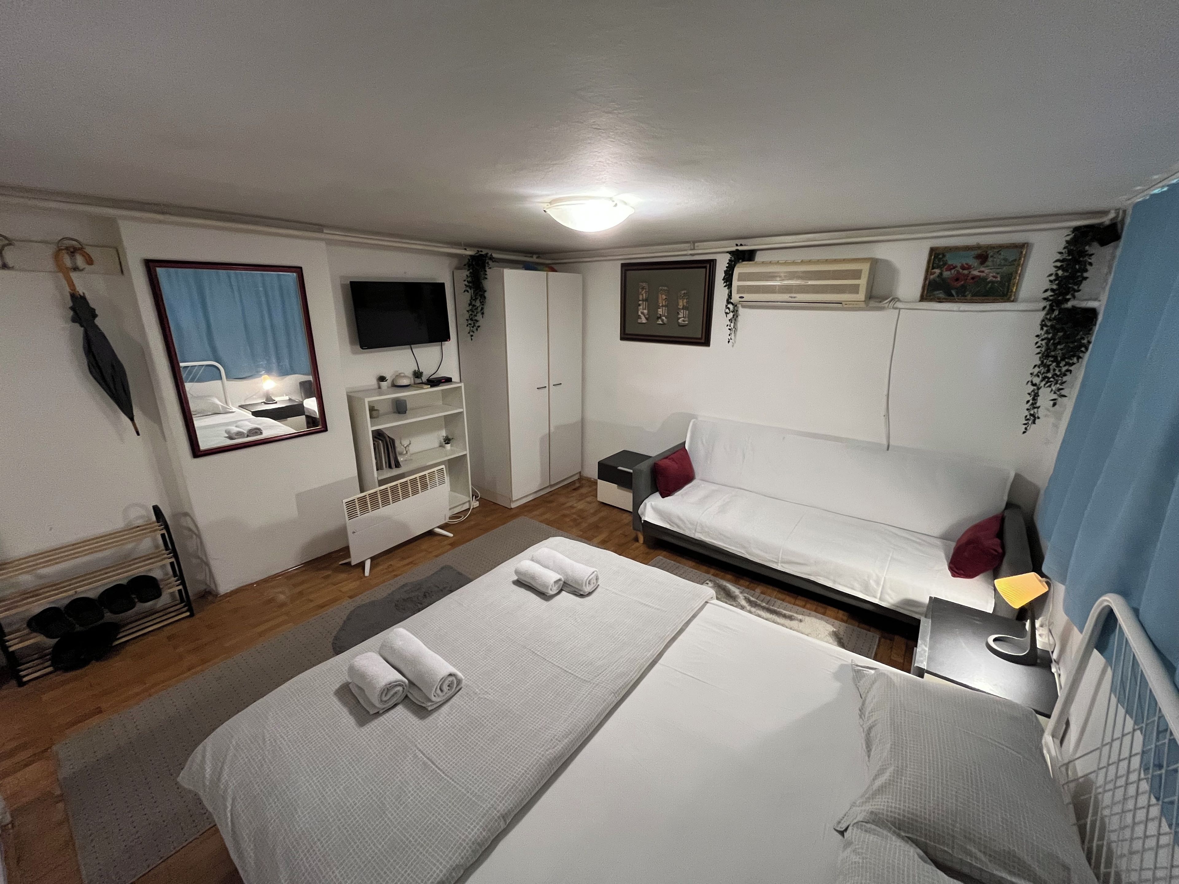 A bedroom with a bed, a sofa, a TV, a wardrobe, and a bedside table.