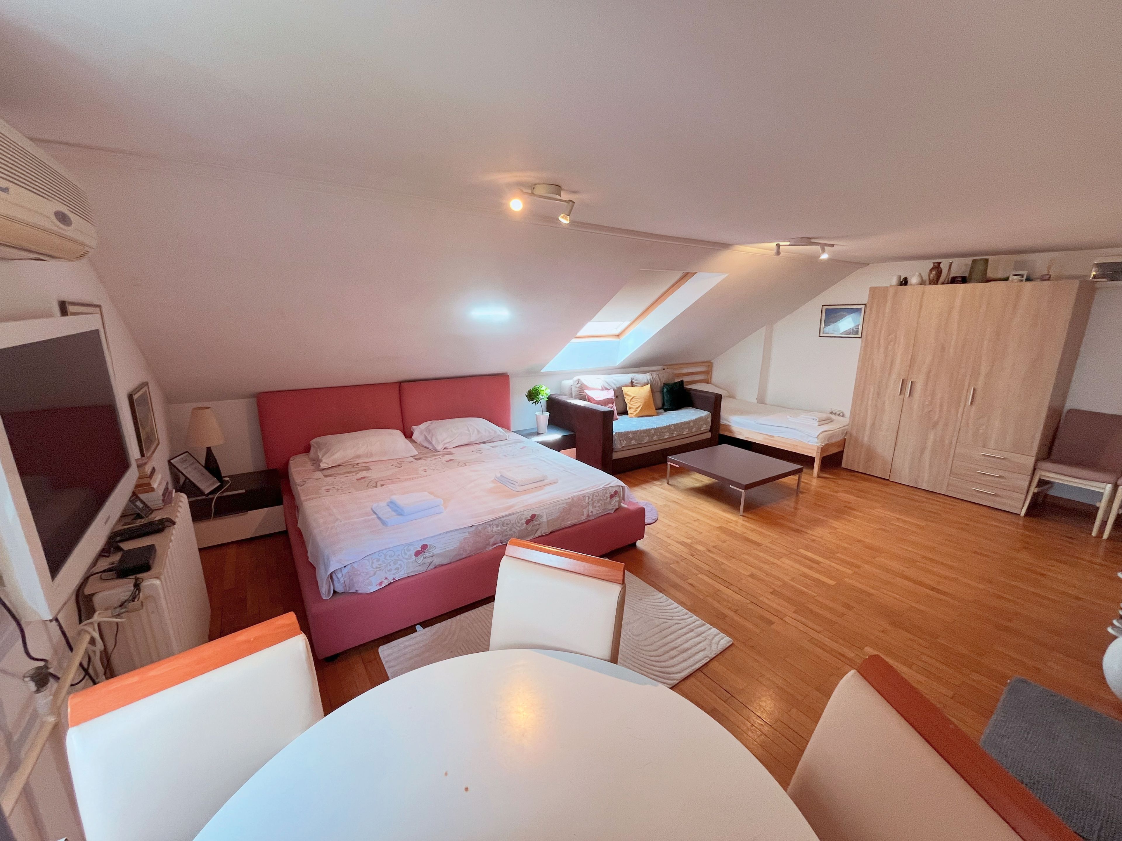 A bedroom with a bed, a desk, a chair, a wardrobe, and a television.