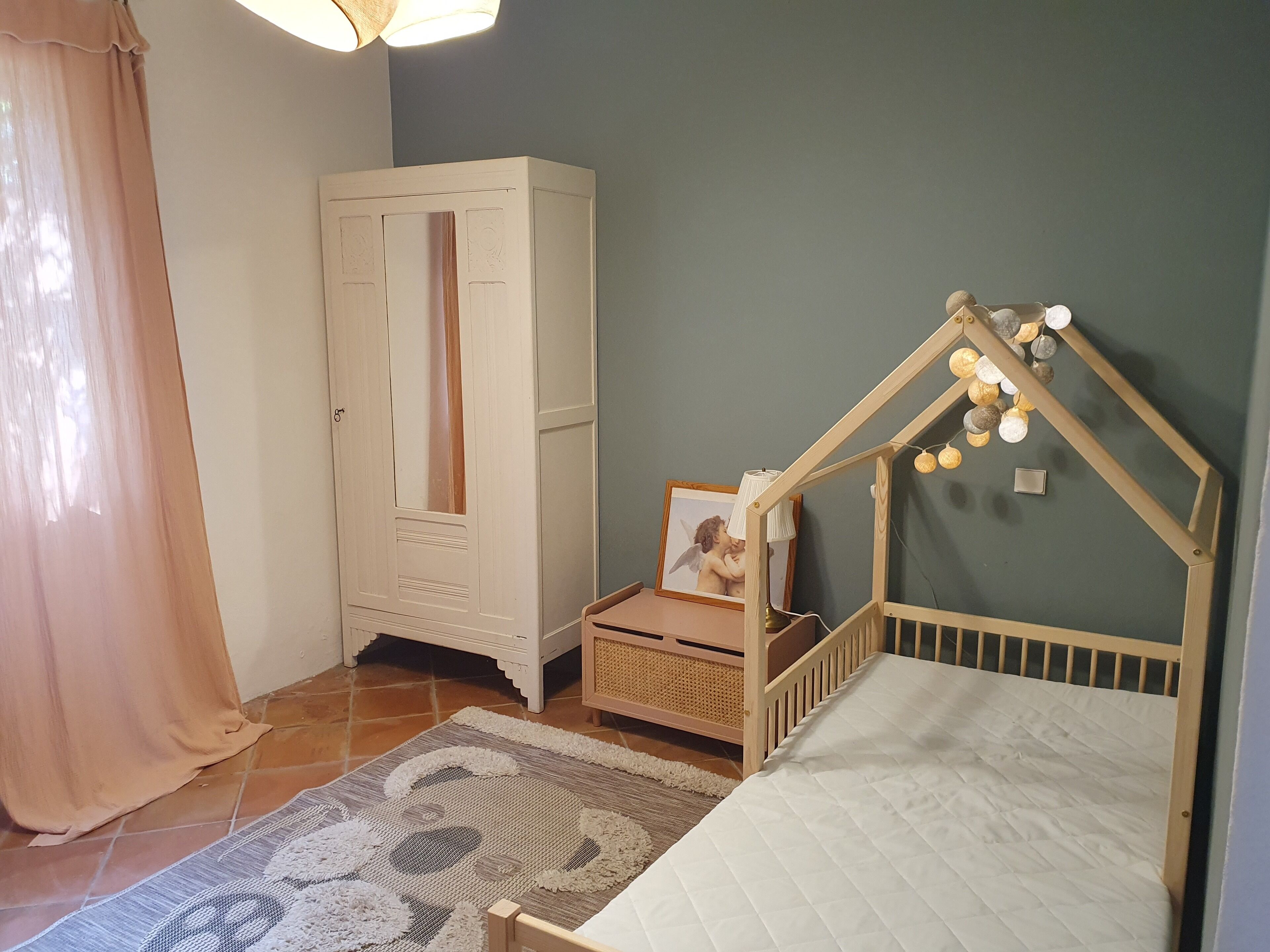 Ein Schlafzimmer mit einem Bett, einem Kleiderschrank, einem Babybett und einer dekorativen Lampe.