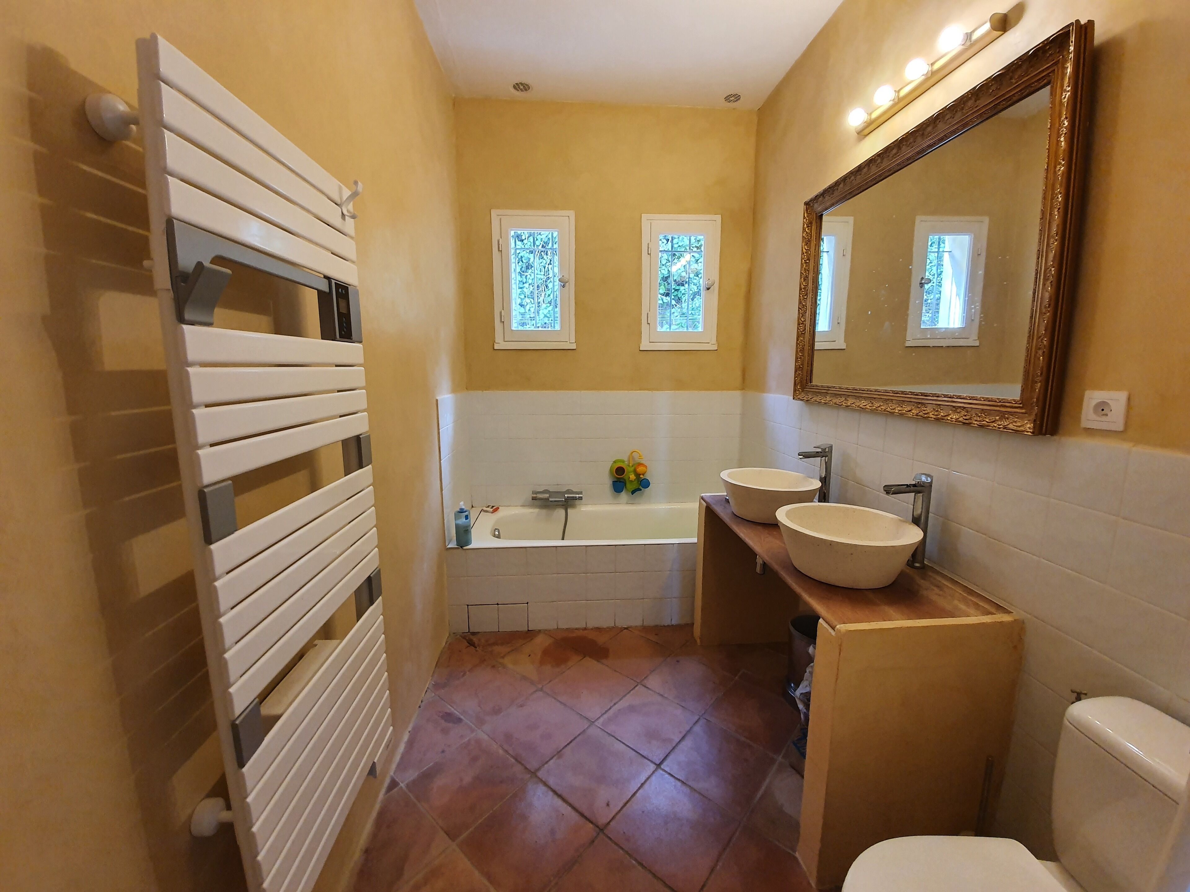 A bathroom with a bathtub, two sinks, a toilet, and a large mirror.