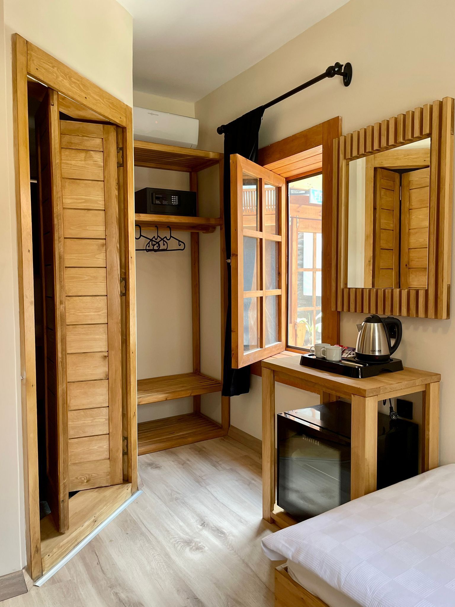 Ein kleines Zimmer, ausgestattet mit einem Holzschrank, einem Tischchen mit Wasserkocher und einem Bett.