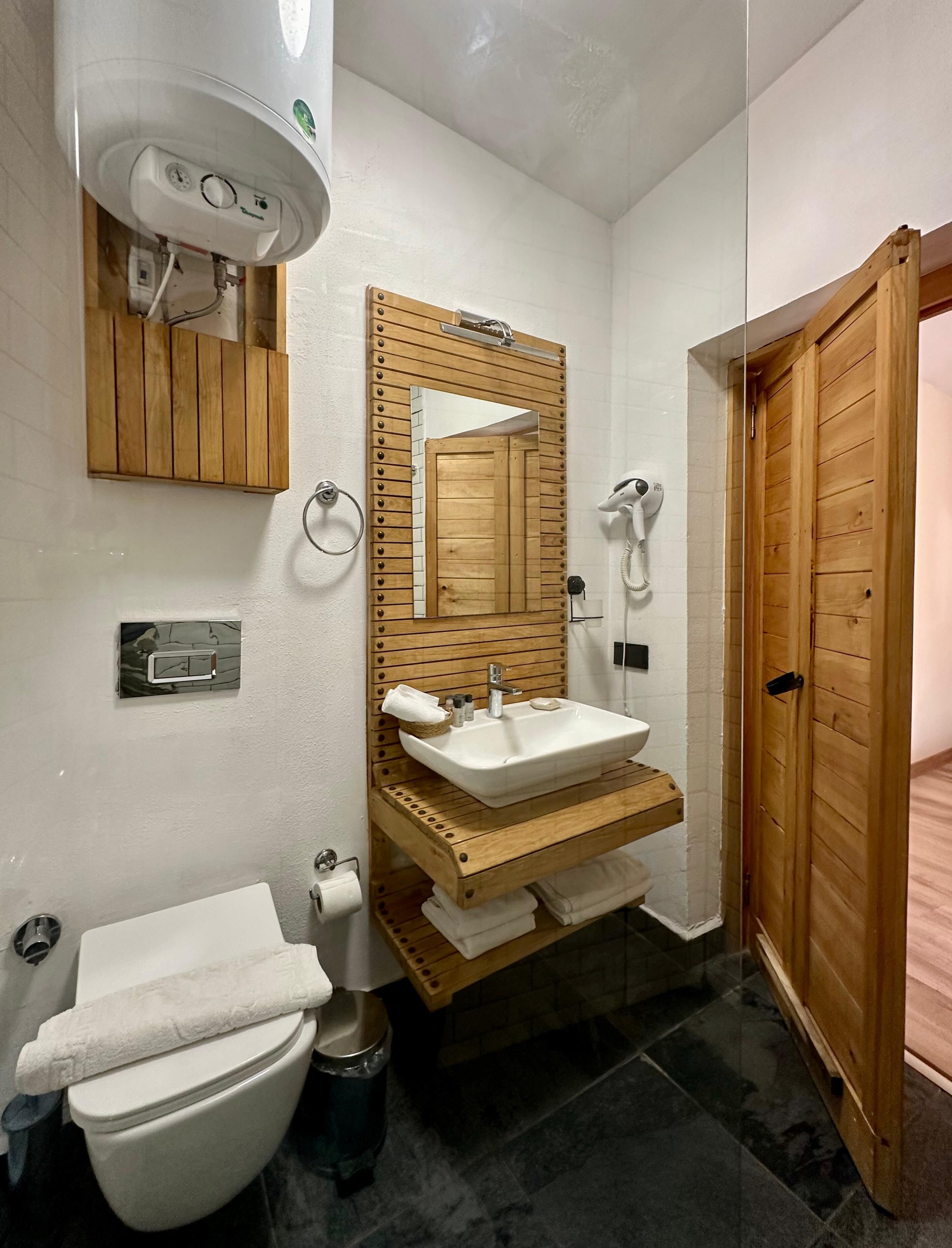 A bathroom with a toilet, sink, and mirror.