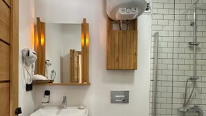 A bathroom with a wooden vanity, a white sink, a toilet, and a glass-enclosed shower.