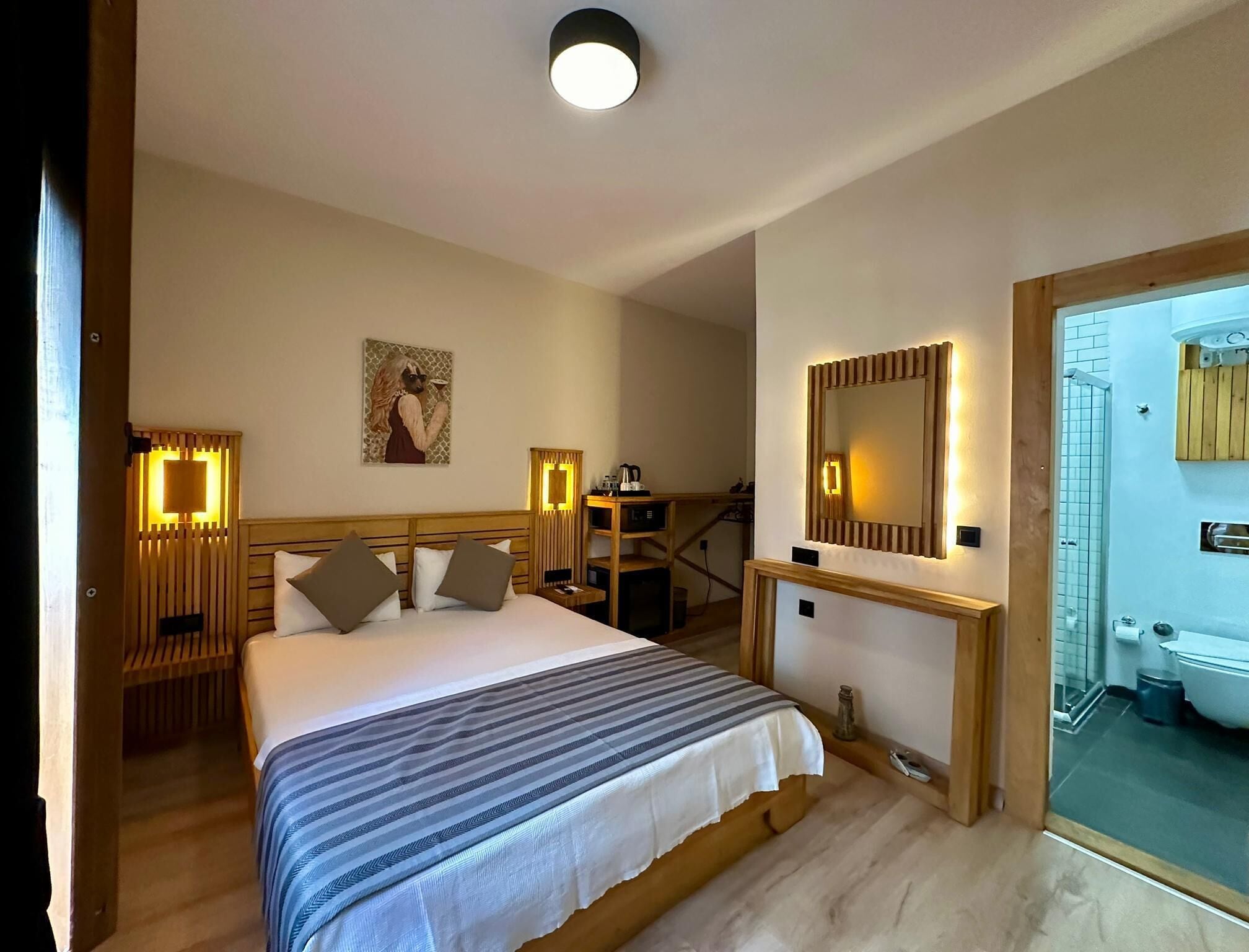 Een hotelkamer met een groot bed, nachtkastjes, een spiegel en uitzicht op de badkamer.