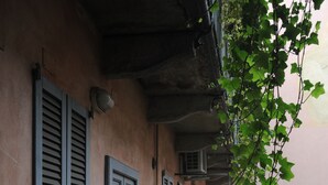 A narrow alleyway with a building featuring shutters and a door. - Ivy house  (Milan)