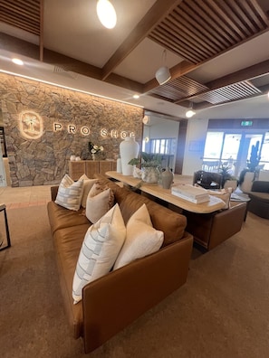 Un área de recepción con pared de piedra, un sofá de cuero marrón y un mostrador de madera.