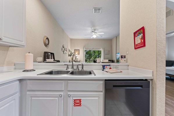 A modern kitchen with a double sink, a ceiling fan, and a dishwasher.