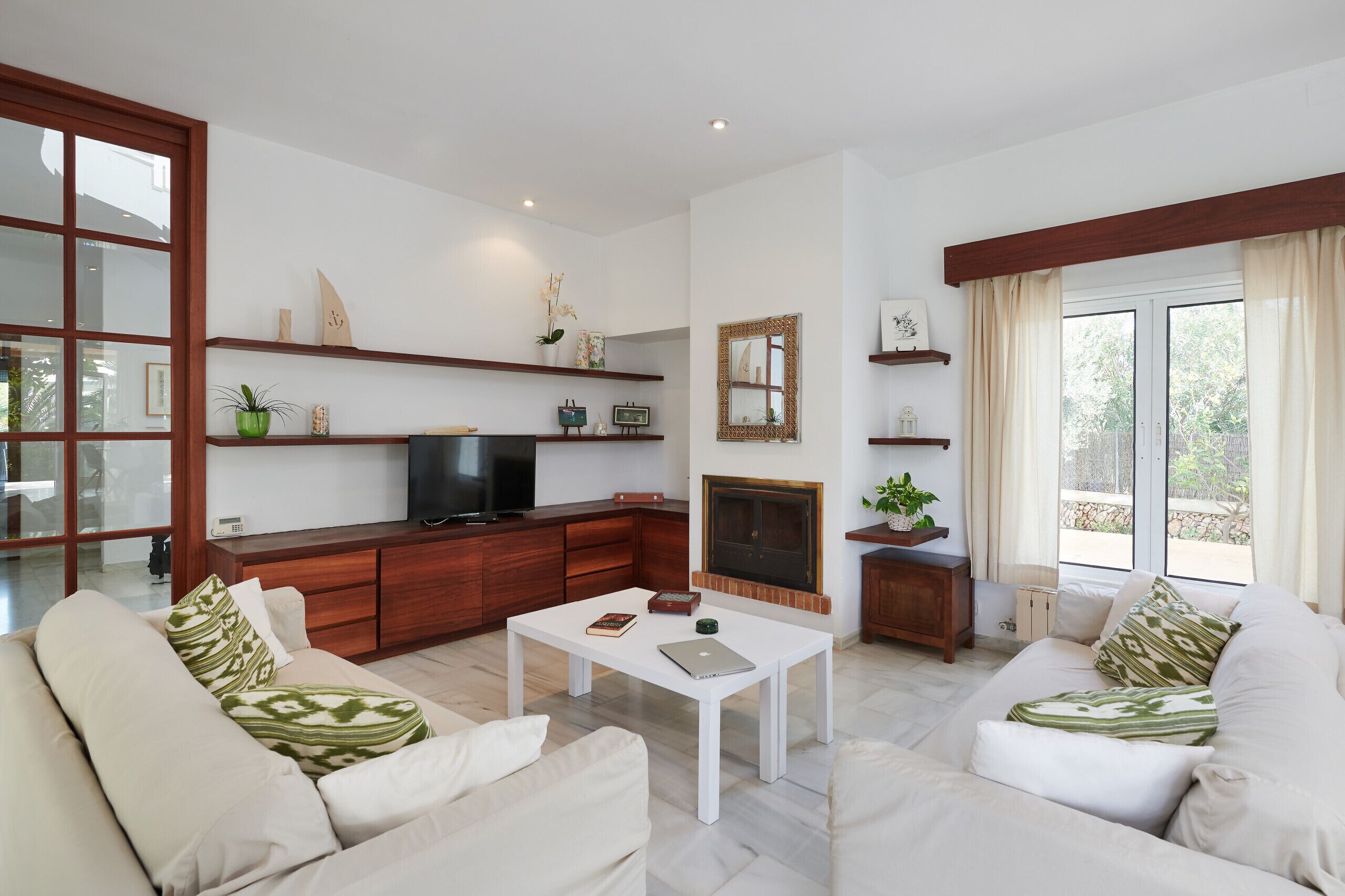 Un salon moderne avec un canapé blanc, une table basse, un téléviseur et une cheminée.