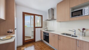 A modern kitchen with a microwave, sink, and stove. - El Faro, frontline apartment with sea views, wifi (Puerto Pollensa)
