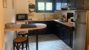 Une cuisine de taille réduite, dotée de meubles de rangement sombres, d’un four à micro-ondes, d’un évier et d’un réfrigérateur.