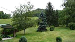 Une pelouse bien entretenue, agrémentée d’un belvédère, de buissons taillés avec soin et de divers arbres.
