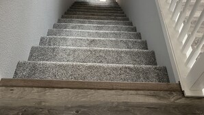 Un escalier muni d’une rampe, menant à une porte située en haut.