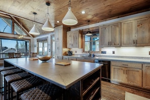 A spacious kitchen with a large island, wooden cabinets, and pendant lighting.