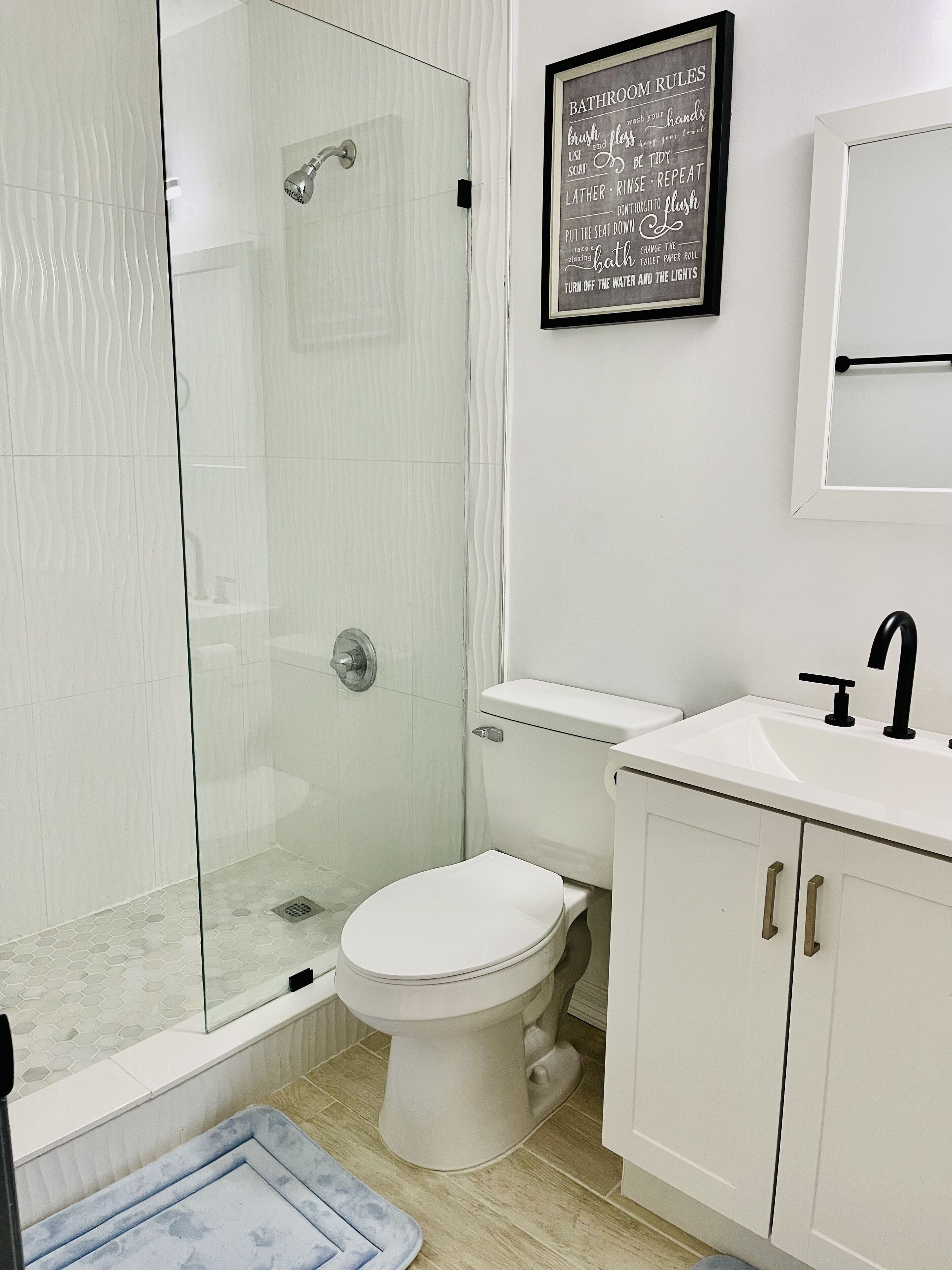 A modern bathroom with a glass-enclosed shower, a white toilet, and a sink with a black faucet.