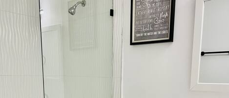 A modern bathroom with a glass-enclosed shower, a white toilet, and a sink with a black faucet.