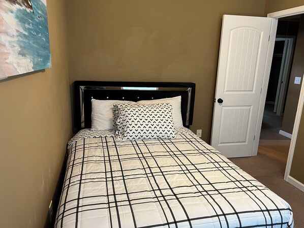 A bedroom with a bed, a patterned bedspread, a headboard, and a door. - Clarksville- Fort Campbell Terrific 4-bedroom Home (Clarksville)