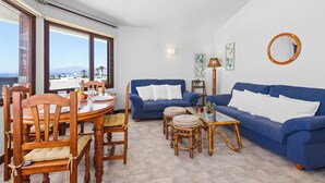 Un salon avec une table à manger, des canapés bleus et une vue sur la mer.